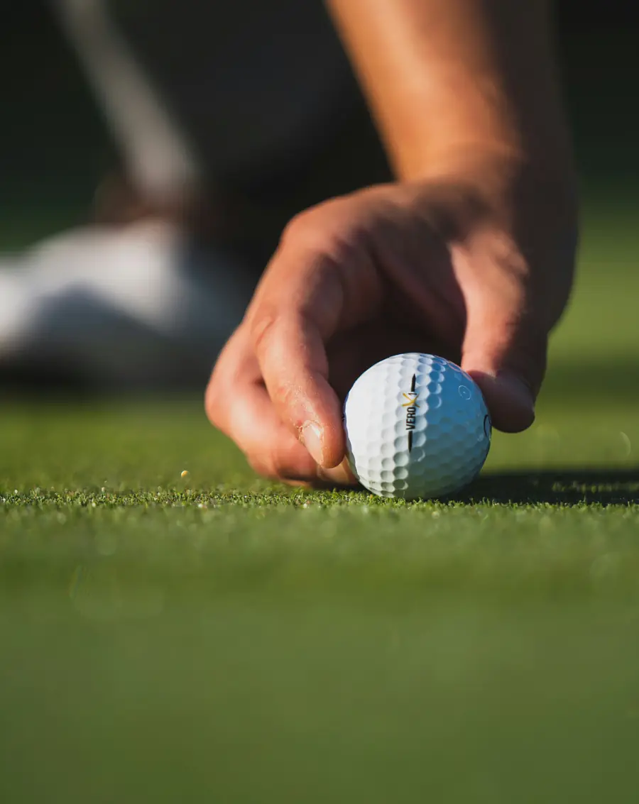 Golfista colocando la bola en el green